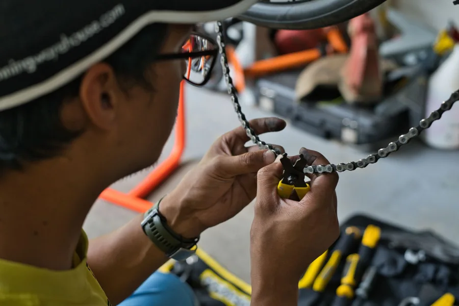 Cyclist joining a chain with a quick-link tool after removing it from the bike
