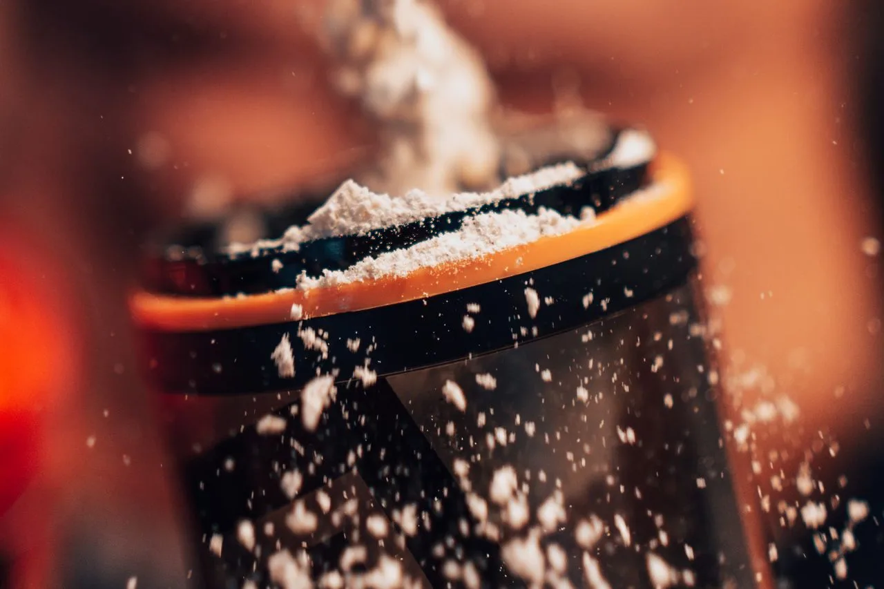 creatine powder being poured into a shaker bottle creatine powder being poured into a shaker bottle