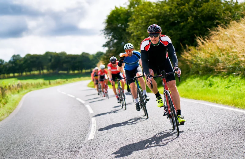 Paceline of road cyclists riding single file on a country road