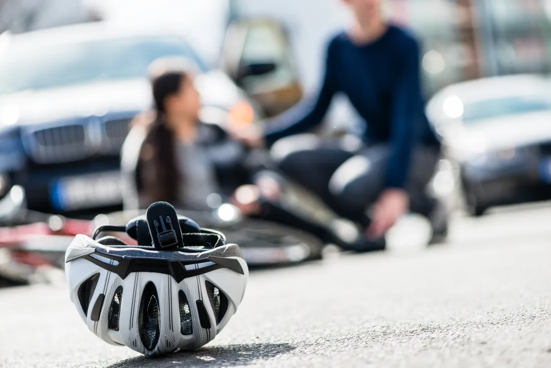 When a motor vehicle is involved, the driver's liability coverage is usually the first place your claim lands Cyclist sitting injured on the road beside a fallen bike and helmet after a collision with a car