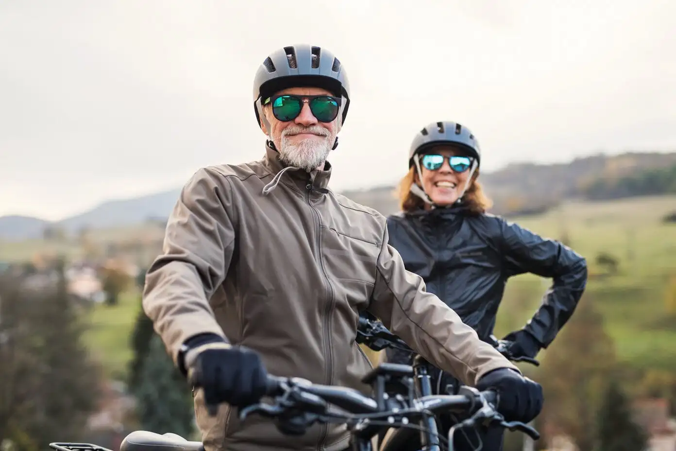 Senior couple with bicycles wearing helmets and sunglasses