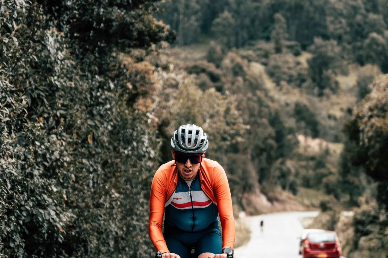On a steep grade, gravity is the main force you are fighting Road cyclist in a helmet and sunglasses climbing a steep rural road up a forested hillside