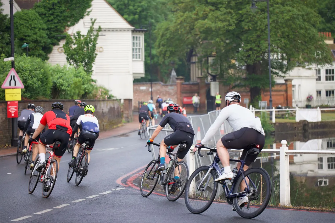 Consistent training is what keeps you with the group when the road tilts up Group of road cyclists riding together up a gentle rise during an organized event