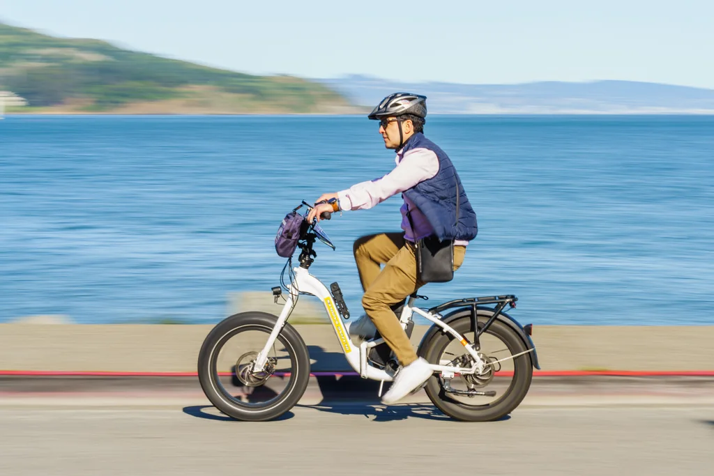 A cyclist riding an electric bike along a waterfront road A cyclist riding an electric bike along a waterfront road
