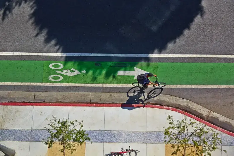 Cyclist in a green-painted bike lane Overhead view of a cyclist riding along a green-painted bike lane marked with a white bicycle symbol and arrow