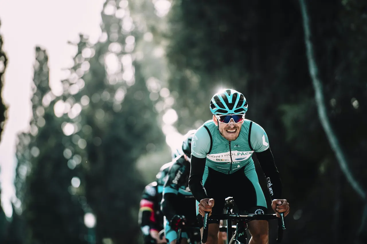 Cycling has no circuit breaker: a motivated rider can pile on intensity for months before anything forces a stop Road cyclist grimacing with effort while riding hard on a tree-lined road