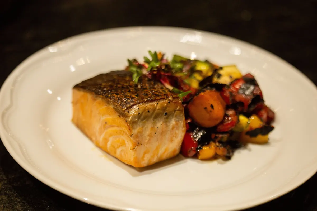 Grilled salmon fillet with roasted vegetables on a white plate, a 35 to 40 gram protein dinner