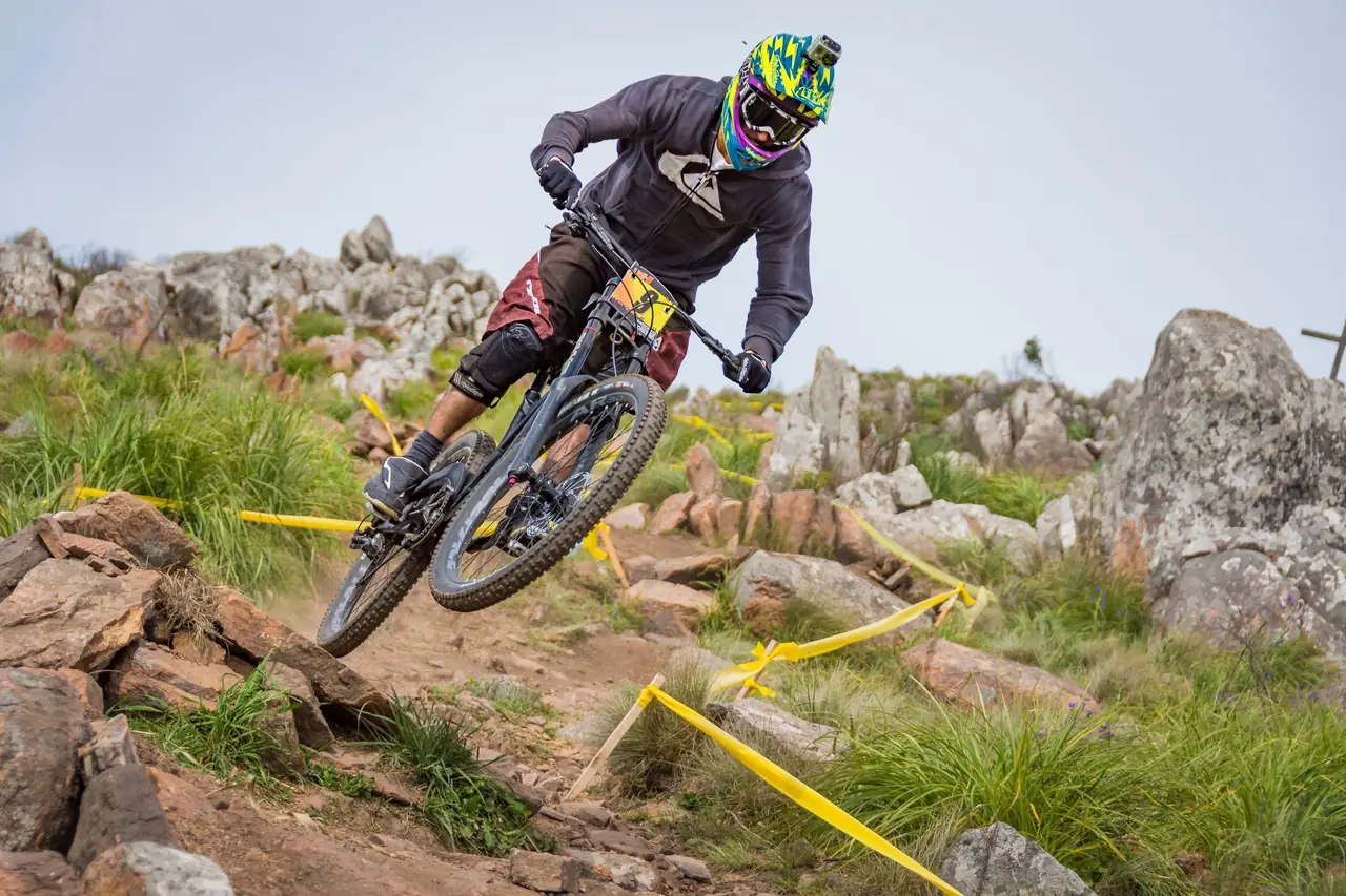 Gravity disciplines carry a risk profile all their own Downhill mountain biker in a full-face helmet riding over rocky terrain on a marked race course