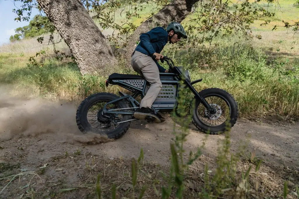 Rider in a helmet kicking up dirt on a high-powered electric dirt bike