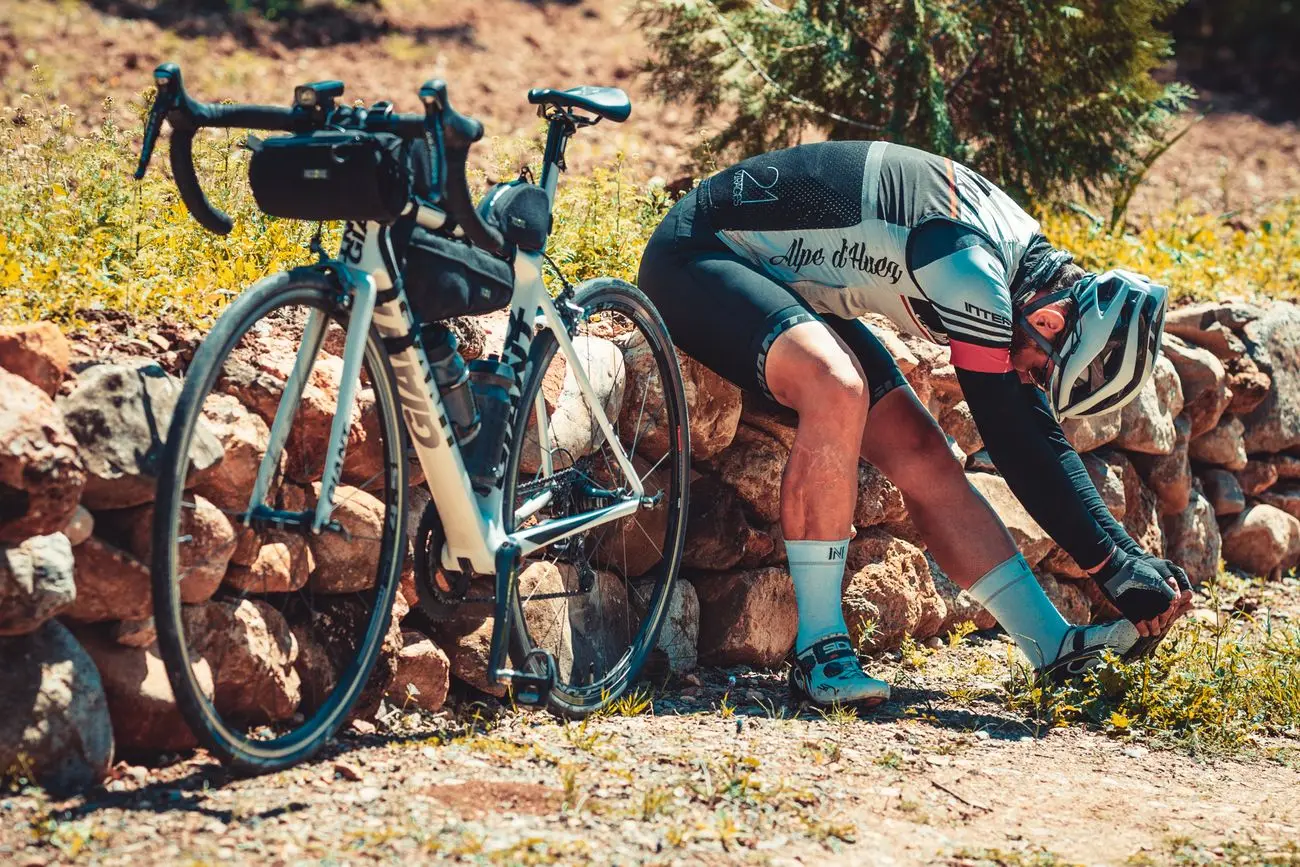 Cyclist stretching beside the bike during a recovery break on a ride