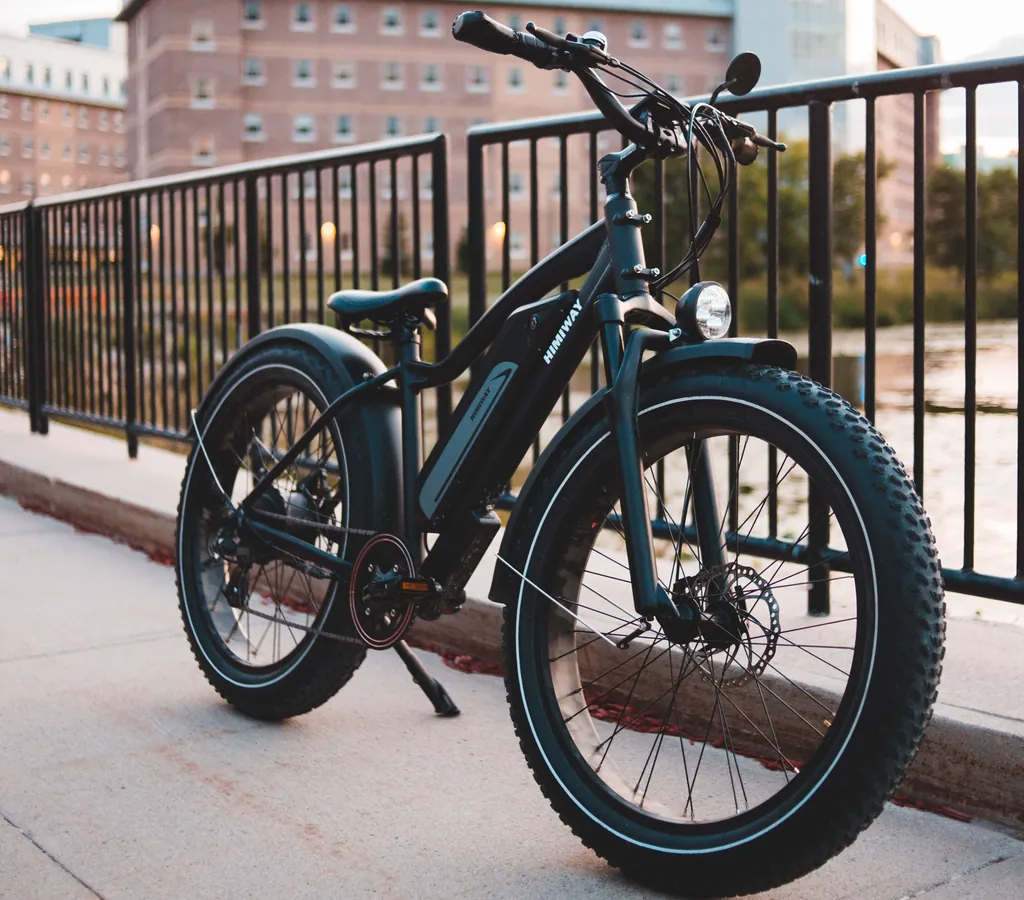 Unlocked fat-tire e-bike standing on its kickstand beside a metal railing Unlocked fat-tire e-bike standing on its kickstand beside a metal railing
